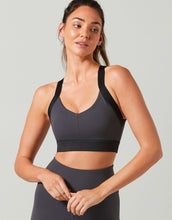 Woman wearing a black sports bra and leggings on a light gray background