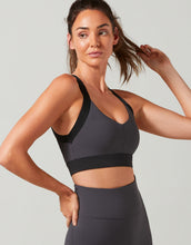 Woman wearing a black sports bra and leggings on a light gray background