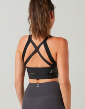 Black sports bra with criss-cross design on a plain background