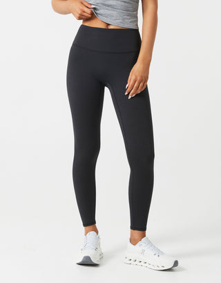 A woman wearing black leggings on a white background.