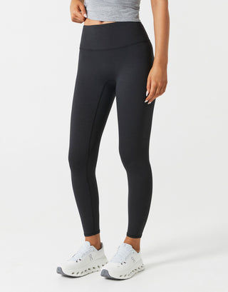 A woman wearing black leggings and white shoes on a white background.