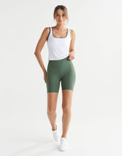 Woman wearing a white tank top and green shorts on a white background