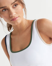 Model wearing a white tank top with green trim on a plain background