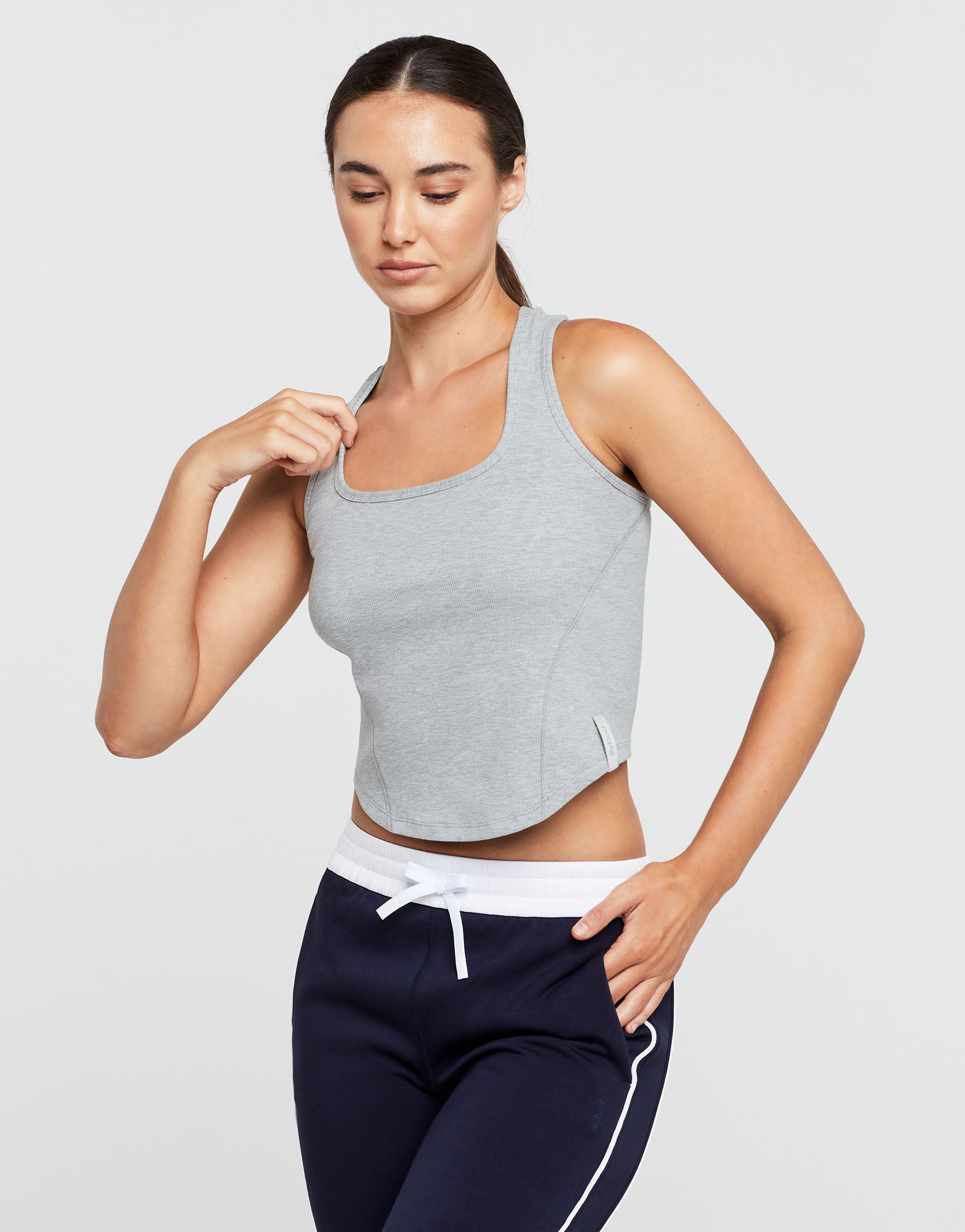 Woman wearing a gray tank top and navy pants on a light gray background