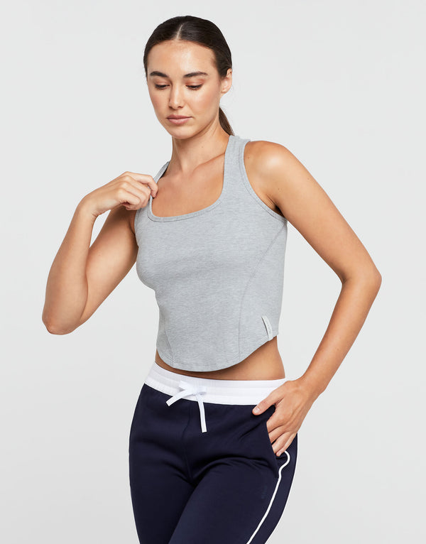 Woman wearing a gray tank top and navy pants on a light gray background