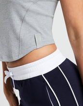 Person wearing a gray crop top and navy pants with white drawstrings on a light background