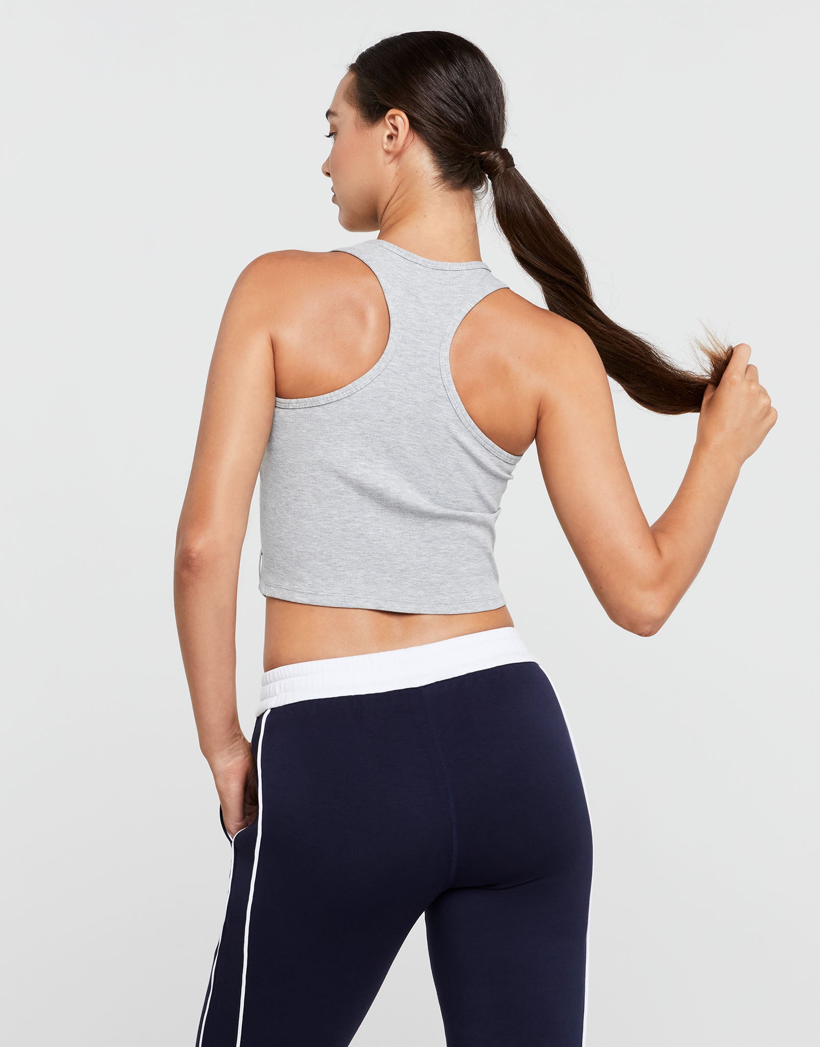 Woman wearing a gray sports bra and navy leggings on a light gray background