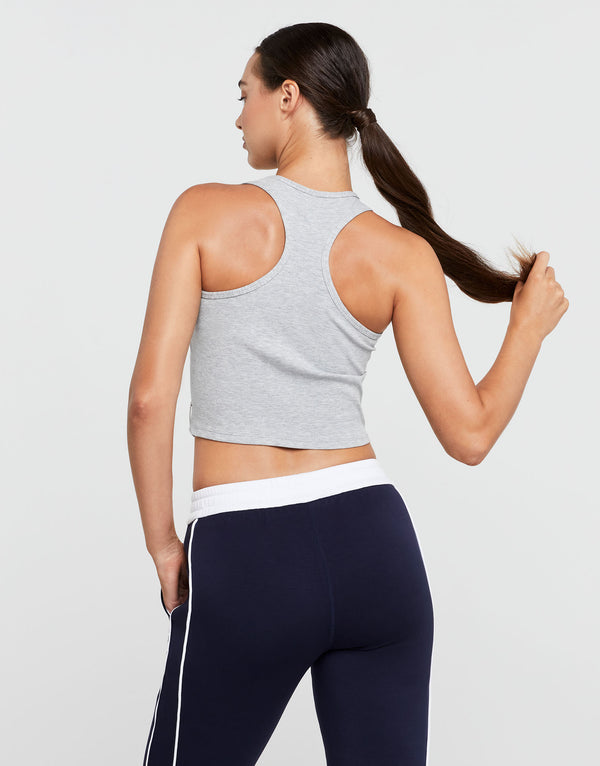 Woman wearing a gray sports bra and navy leggings on a light gray background