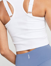 White sports bra and blue leggings with a brand logo on a neutral background
