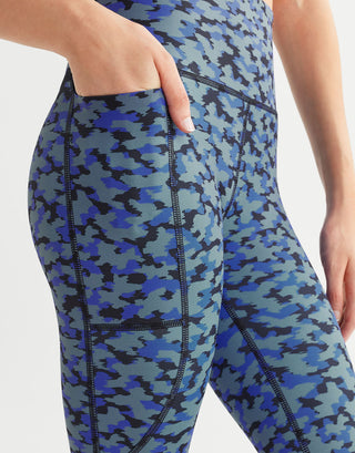 A woman wearing blue printed leggings with pockets on a white background.
