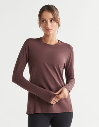 Woman wearing a brown long-sleeve top on a light gray background