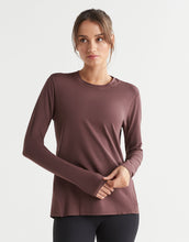 Woman wearing a brown long-sleeve top on a light gray background