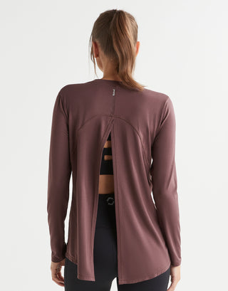 Woman wearing a long-sleeve brown top with a cutout design on a white background