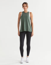 Woman wearing a green tank top and black leggings on a white background
