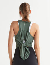 Person wearing a green tank top with a knot detail on a white background