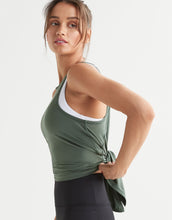 Woman wearing a green tank top with a white trim on a light gray background