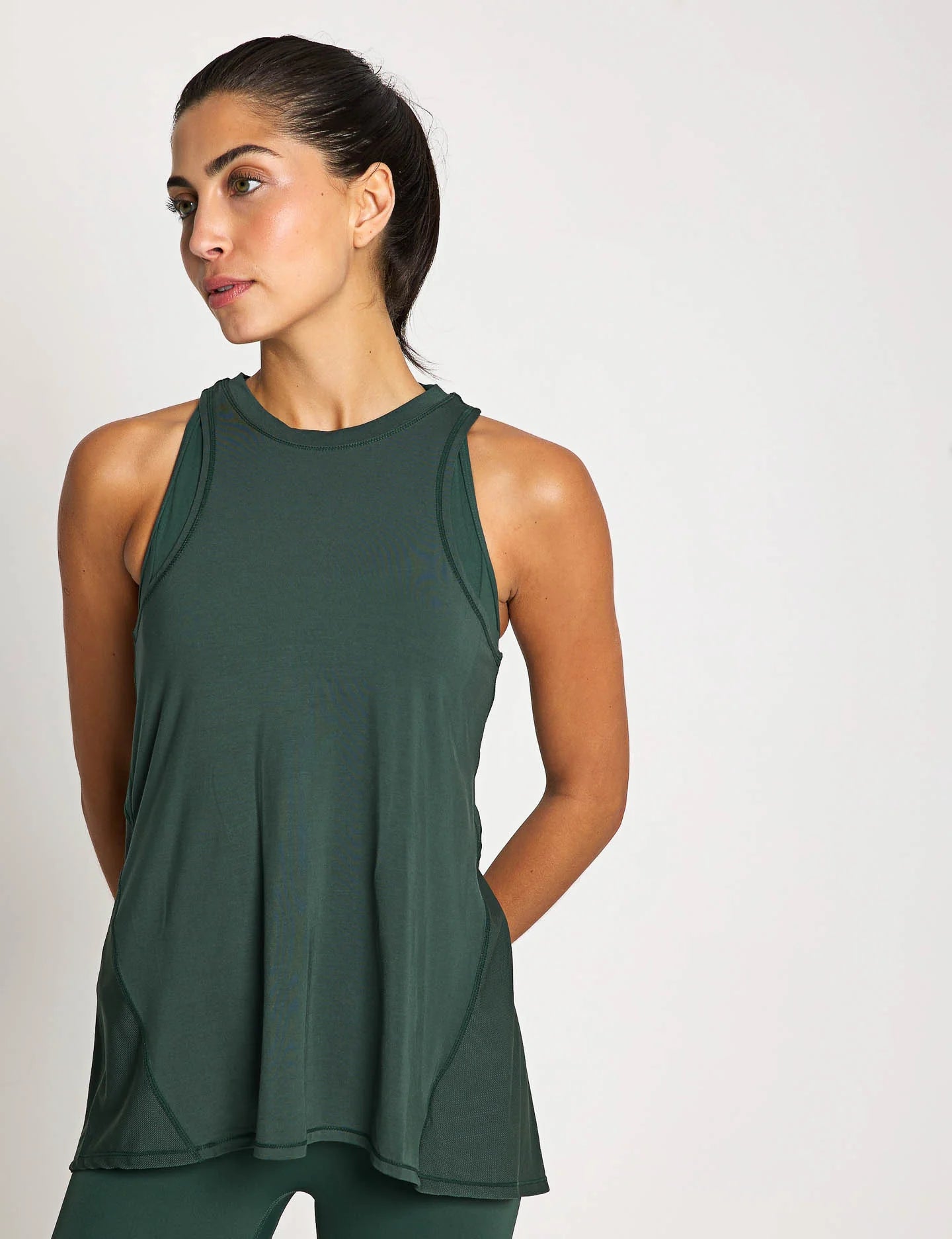 Woman wearing a green sleeveless top against a plain background
