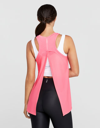 Woman wearing a pink sleeveless top with a white shirt underneath on a gray background