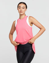 Woman wearing a pink sleeveless top and black leggings on a light gray background