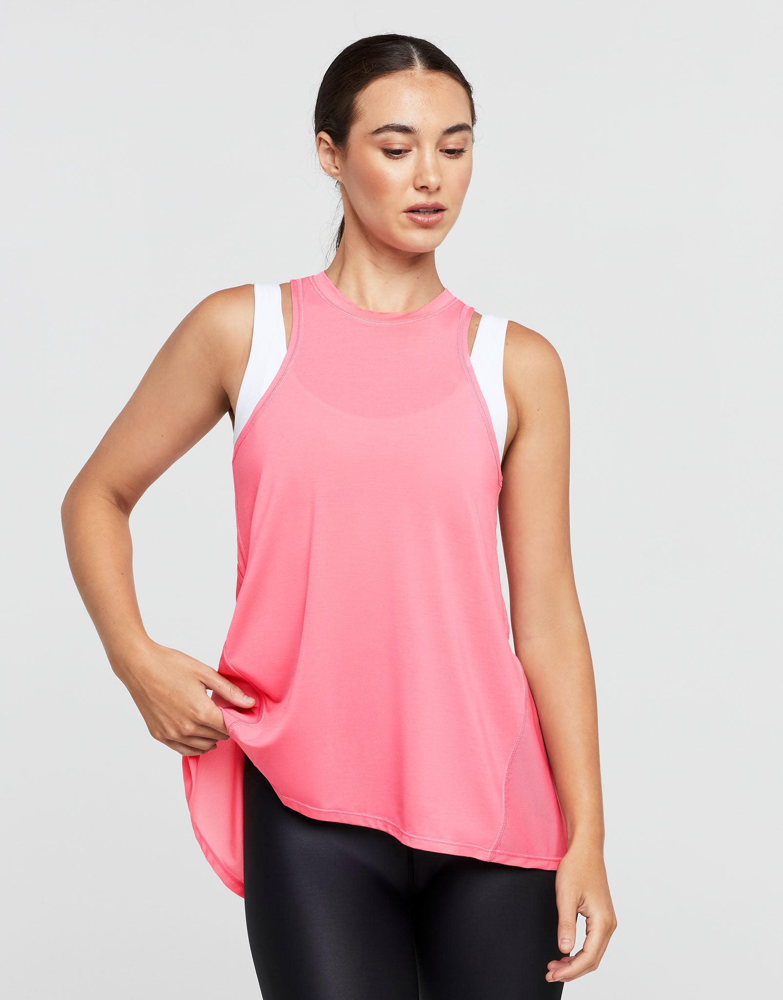 Woman wearing a pink sleeveless top with white trim on a light gray background