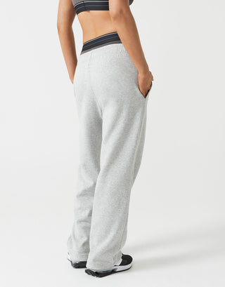 A woman wearing grey sweatpants and a sports bra from the rear.