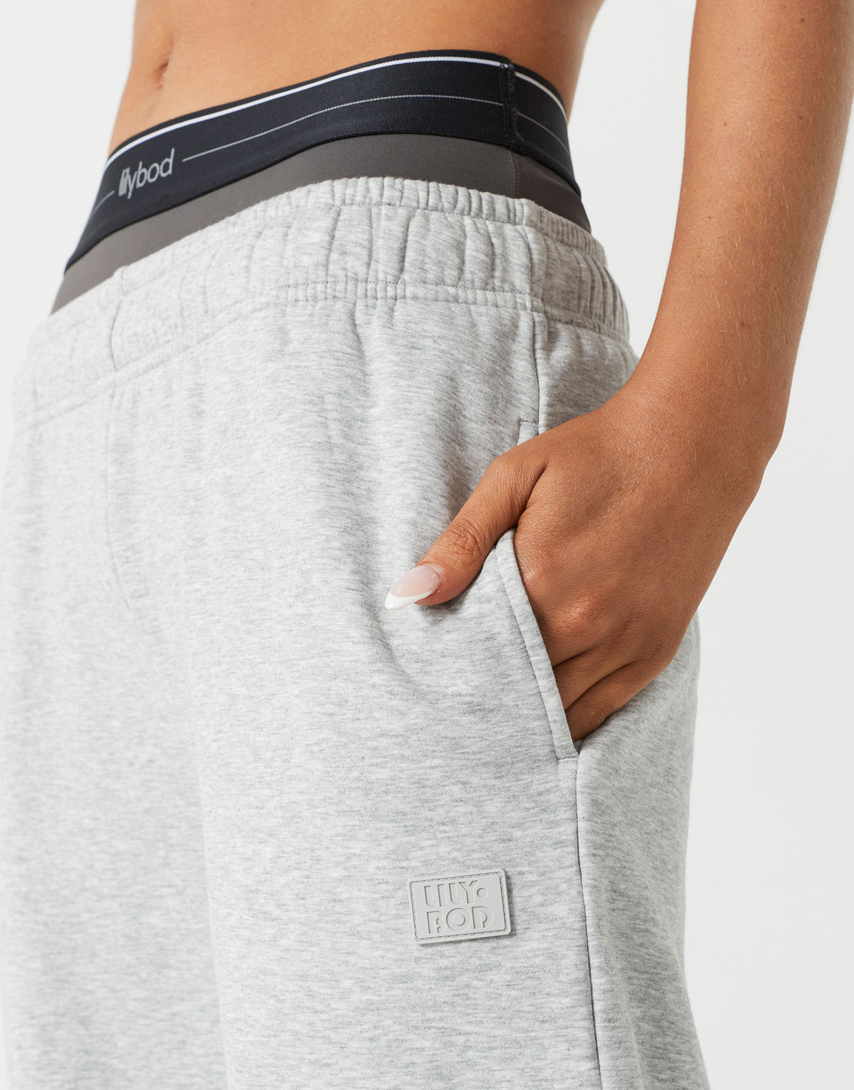 A  close up of a woman wearing grey sweatpants and a sports bra.
