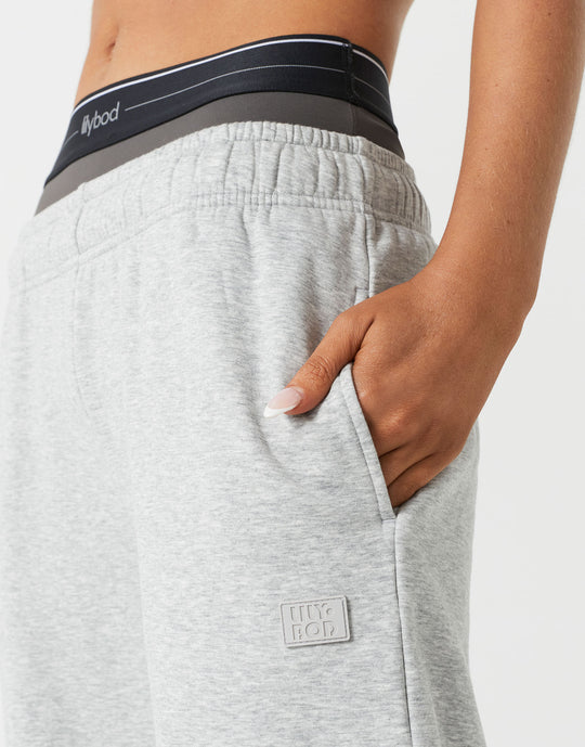 A  close up of a woman wearing grey sweatpants and a sports bra.