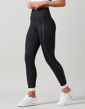 Black leggings with white accents worn by a model on a light gray background