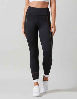 Black leggings with white accents worn by a person on a gray background