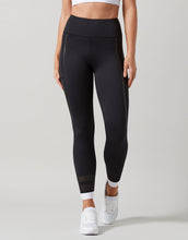 Black leggings with white accents worn by a person on a gray background