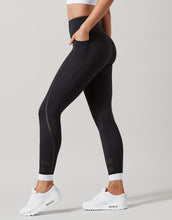 Black leggings with white accents worn by a person on a gray background