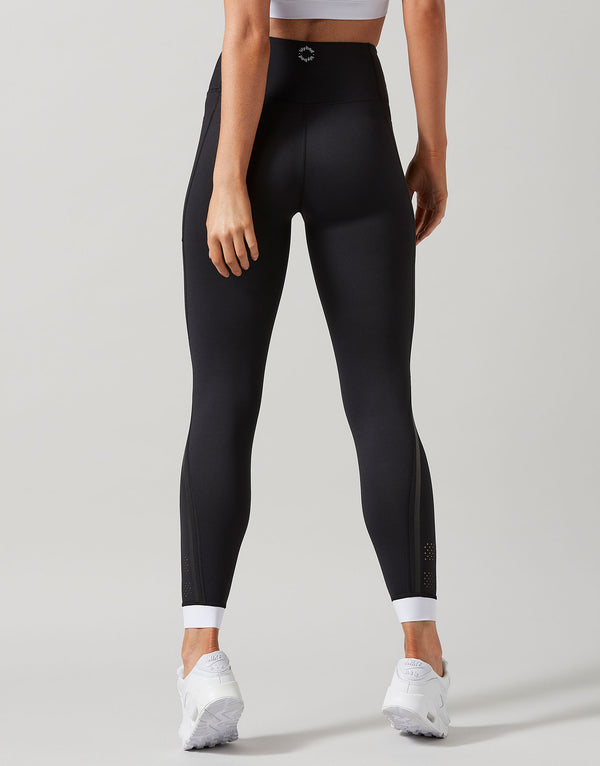 Person wearing black leggings with white accents on a plain background