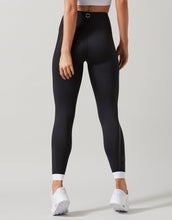 Person wearing black leggings with white accents on a plain background