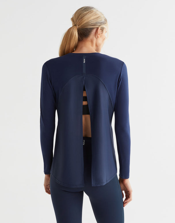 Rear view of a woman wearing a navy blue long sleeved top with a split back and blue leggings