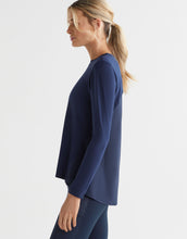 Woman wearing a navy blue long-sleeve top on a light gray background
