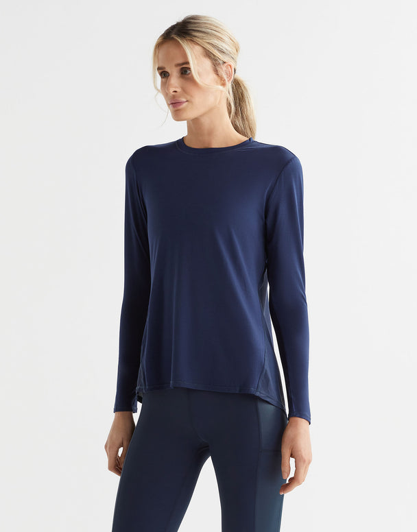 A woman standing wearing a navy long sleeved tie-up top and black leggings