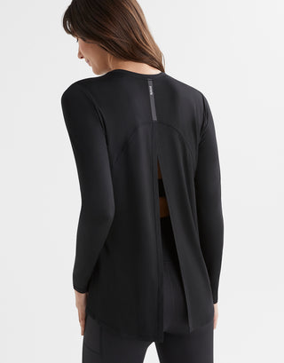 Black activewear top with open back worn by a person on a light grey background