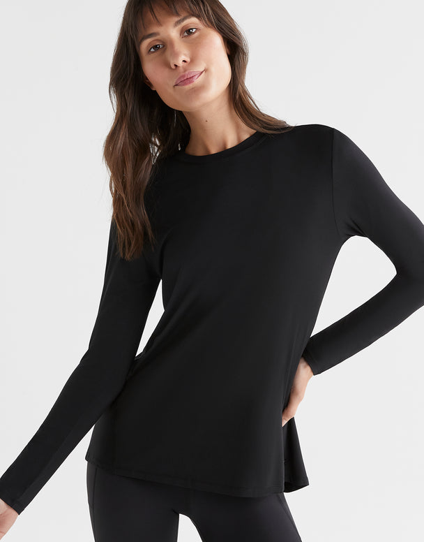 Woman wearing a black long-sleeve top against a white background