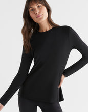 A woman wearing a long sleeve black tie-up top with a relaxed fit.