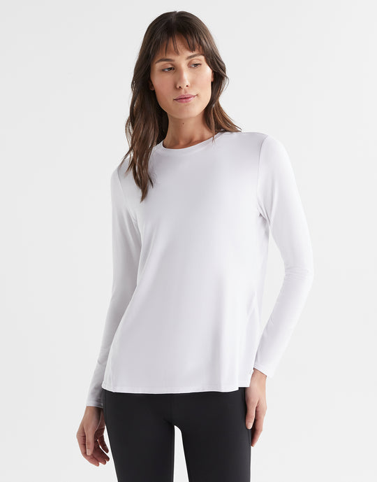 Woman wearing a white long-sleeve top against a white background