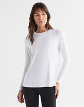 Woman wearing a white long-sleeve top against a white background