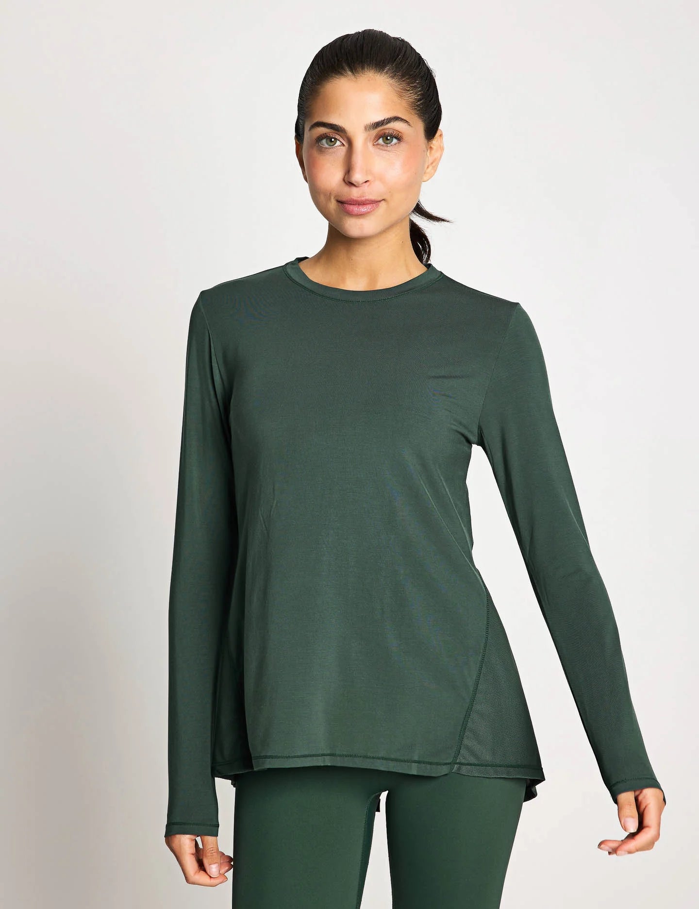 Woman wearing a green long-sleeve top and pants on a white background