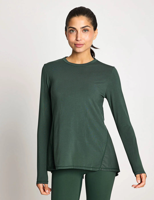 Woman wearing a green long-sleeve top and pants on a white background