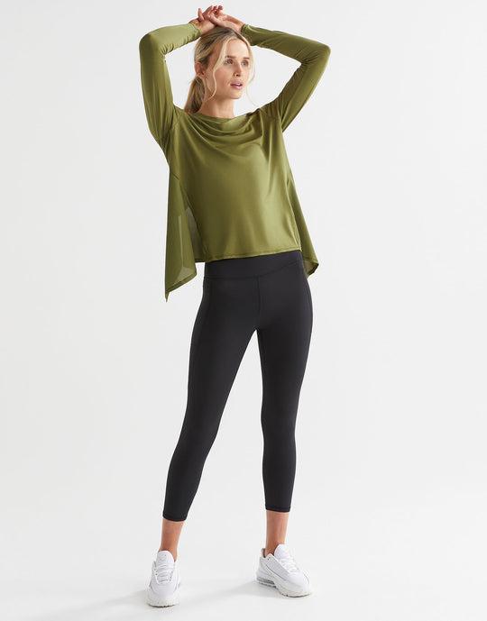 A model wearing an army green long sleeve tie-up top with black leggings.