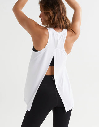 A woman wearing a white tank top and black leggings from the back.