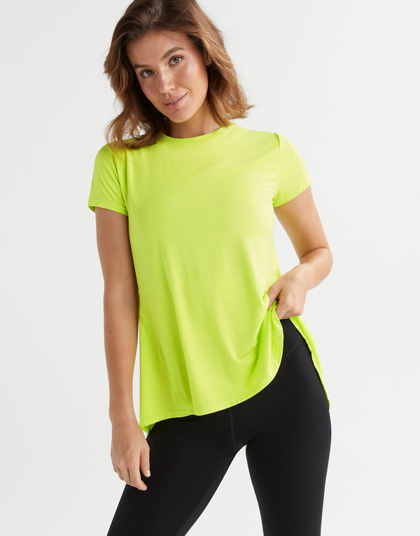 Woman wearing a bright green t-shirt and black leggings on a white background