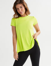 Woman wearing a bright green t-shirt and black leggings on a white background
