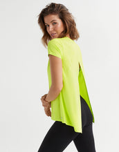 Woman wearing a bright green t-shirt and black leggings on a white background