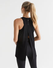 Person wearing a black sleeveless top with a unique back design on a white background