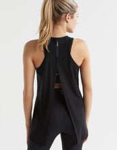 Woman wearing a black sleeveless top with a unique back design on a white background